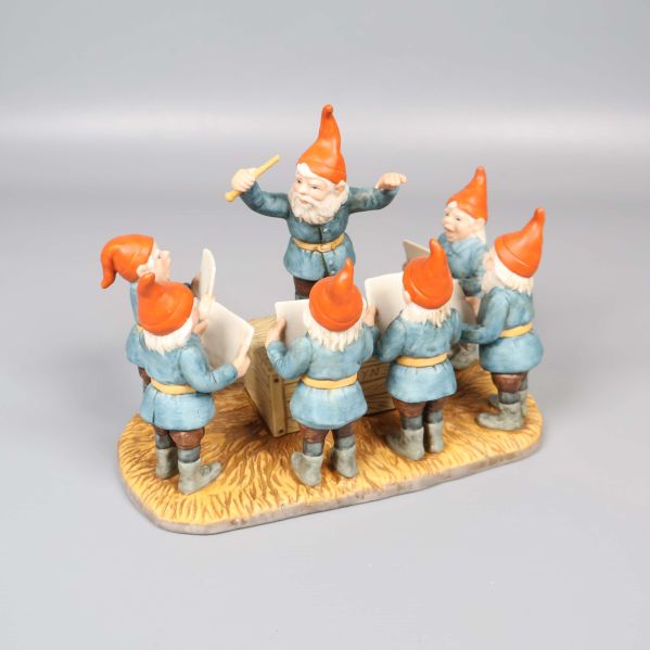 Tomtekör med dirigent i blå kläder och röda luvor