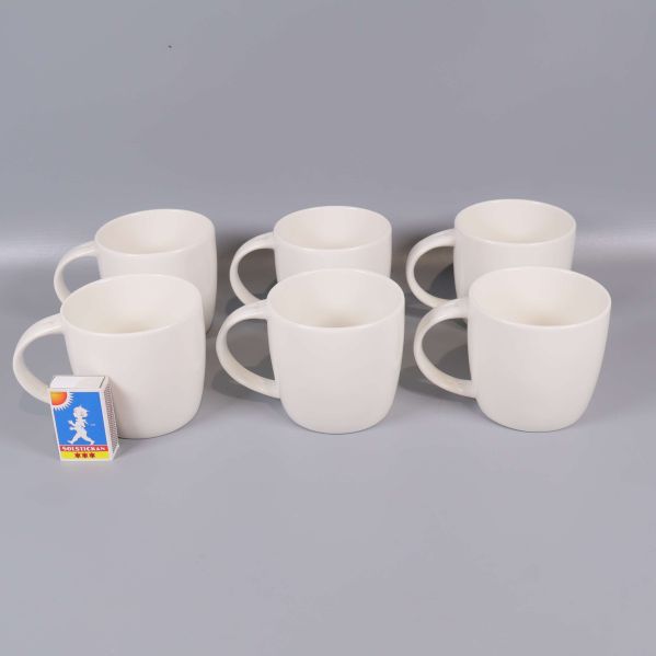 Sex vita muggar på rad med tändsticksask som storleksreferens