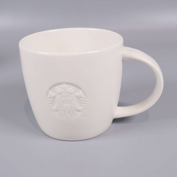 Närbild på vit mugg med Starbucks-relief