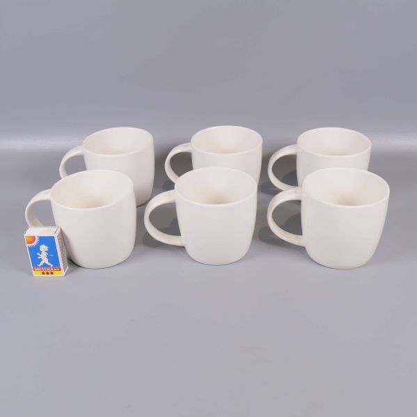 Sex vita muggar varav en med tändsticksask för storleksreferens