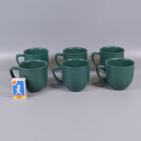 Sex gröna kaffekoppar bredvid en tändsticksask för storleksjämförelse