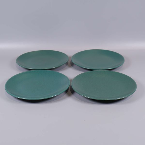 Fyra runda mörkgrön keramikassietter uppifrån