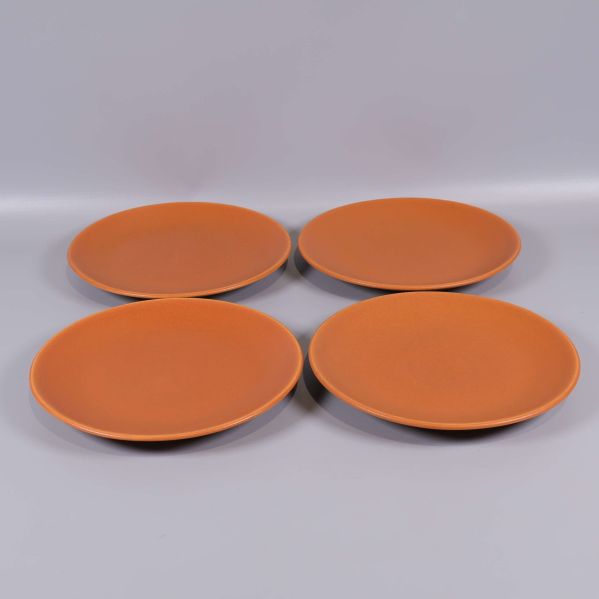 Fyra orangea keramikassietter i grupp mot grå bakgrund