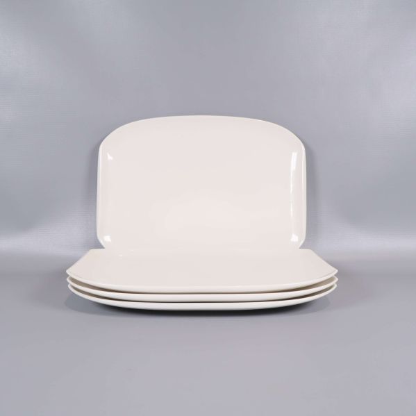 Fyra staplade rektangulära vita tallrikar mot grå bakgrund