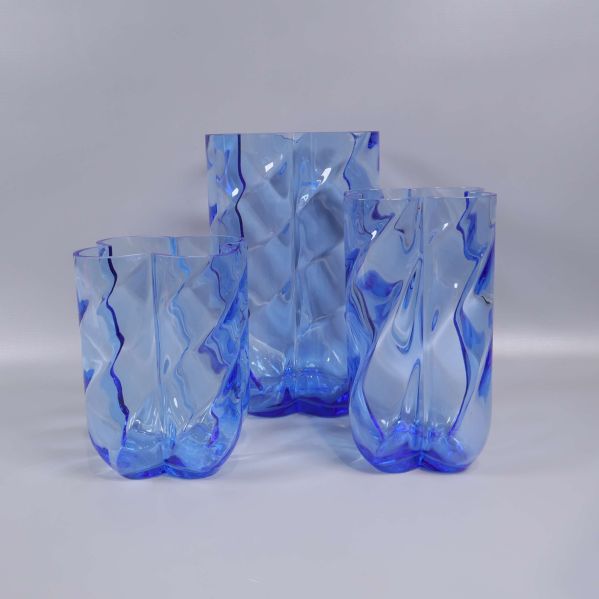 Tre blå glasvaser med vågig form i grupp