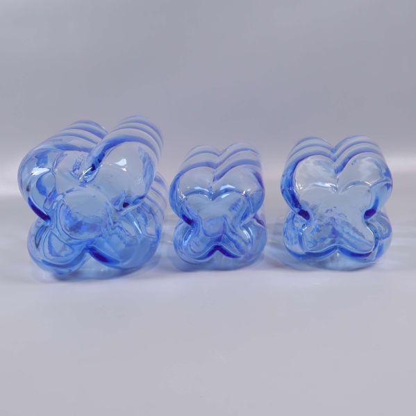 Undersidan av tre blå glasvaser med blomformad bas