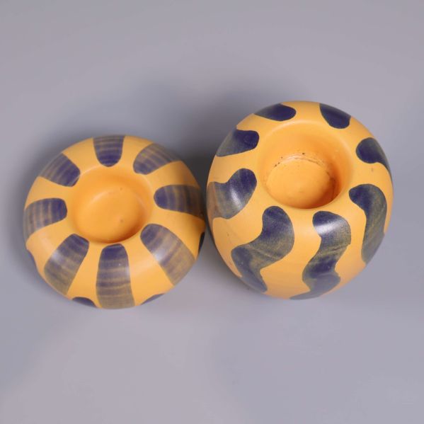 Tvåfärgade ljushållare sedda ovanifrån på grå bakgrund