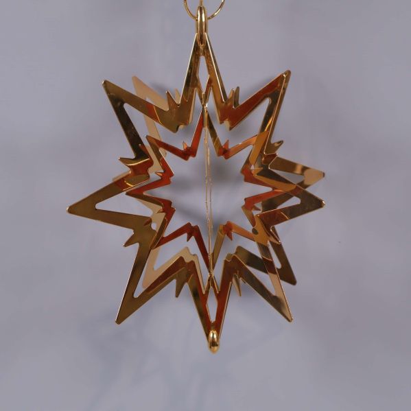 Guldfärgad metallstjärna mot grå bakgrund