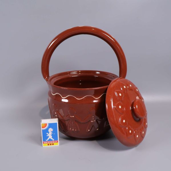 Keramikburk med öppet lock och tändsticksask som storleksreferens