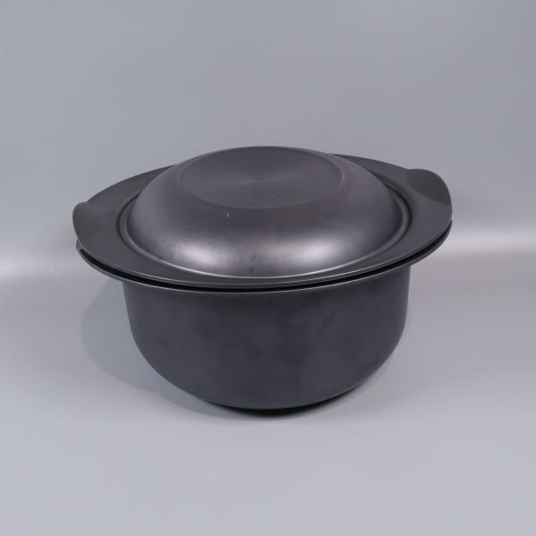 Svart gryta med lock mot ljus bakgrund