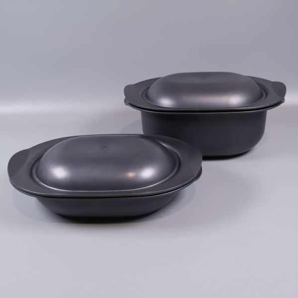 Två svarta gratängformar med lock på grå bakgrund