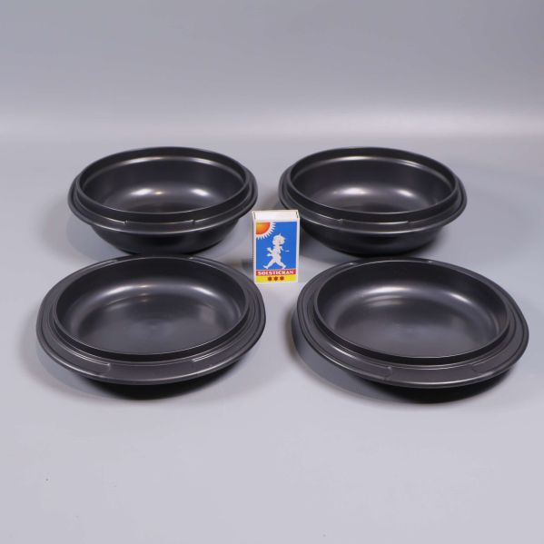 Fyra svarta skålar med tändsticksask som storleksjämförelse