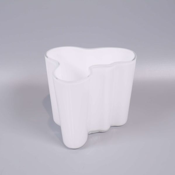 Vit vågig vas stående på ljusgrå bakgrund