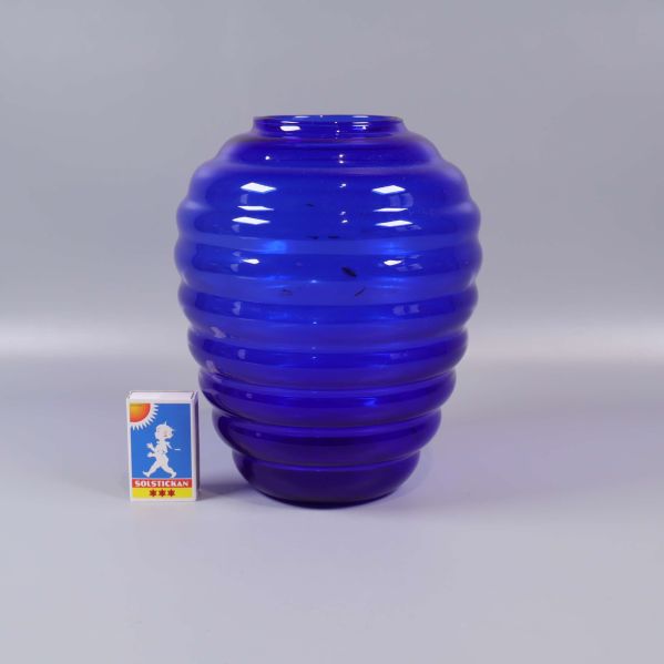 Blå räfflad vas bredvid tändsticksask för storleksreferens