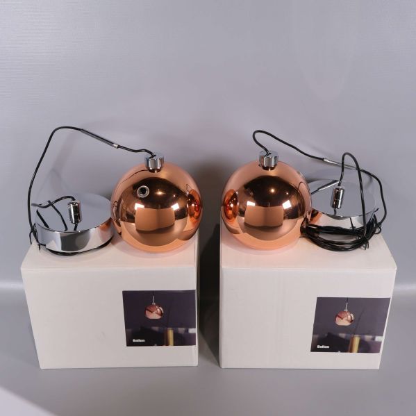 Två kopparfärgade klotformade pendellampor på kartonger