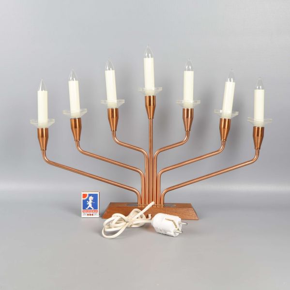 Elektrisk ljusstake med vit sladd och stickpropp framför grå bakgrund