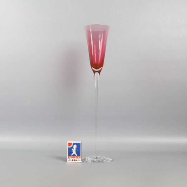 Högt glas med rosa kupa och en tändsticksask bredvid för storleksreferens