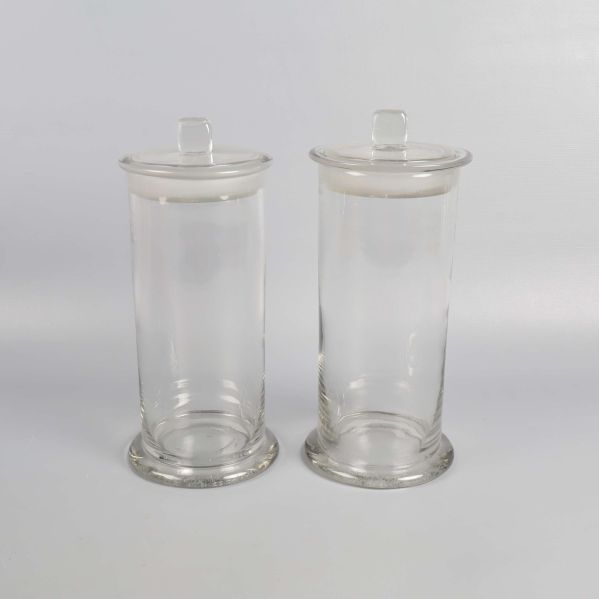 Två höga glasburkar med lock på vit bakgrund