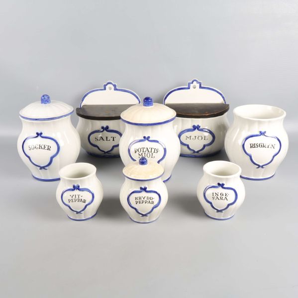 Åtta vita porslinsburkar med blå detalj och inskriptioner
