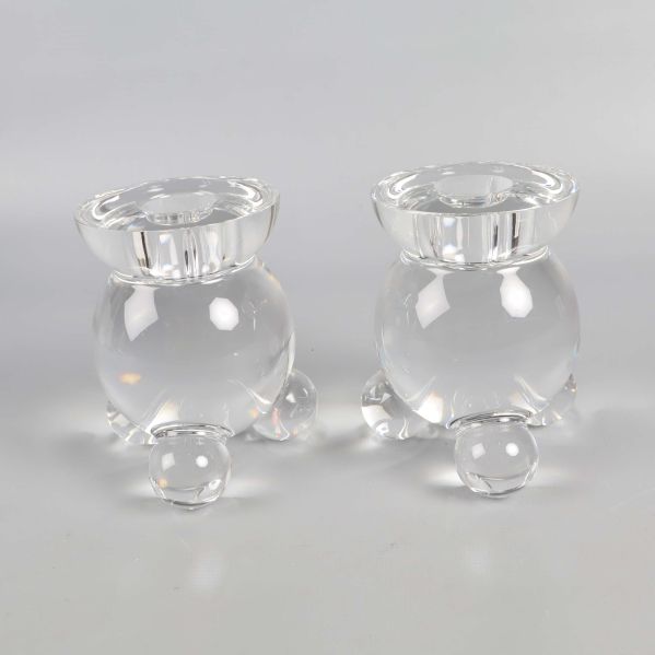 Närbild på två klara runda glasljusstakar med tre ben