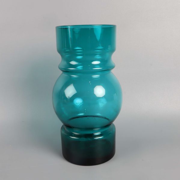 Grön glasvas fotad rakt framifrån mot ljus bakgrund