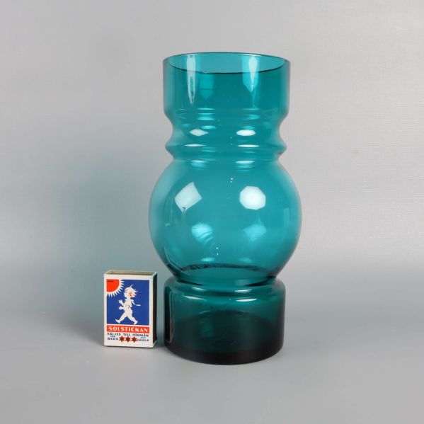 Grön glasvas bredvid tändsticksask för storleksjämförelse