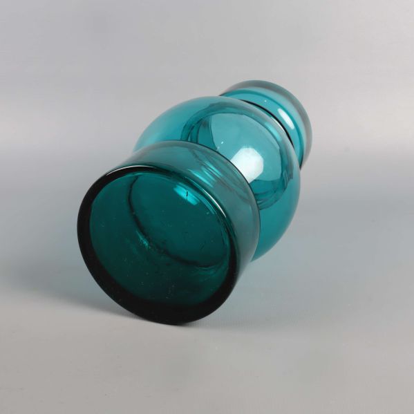 Grön glasvas liggande på sidan mot vit bakgrund