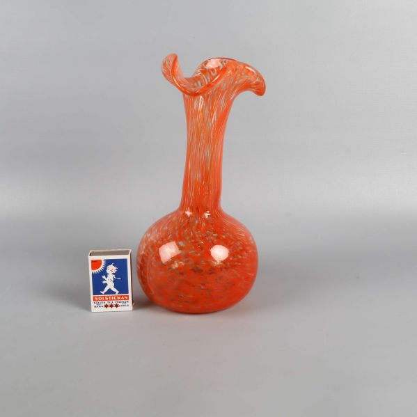 Handblåst orange vas bredvid tändsticksask för storleksjämförelse