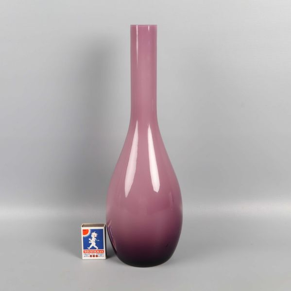 Lilarosa vas bredvid tändsticksask för storleksreferens