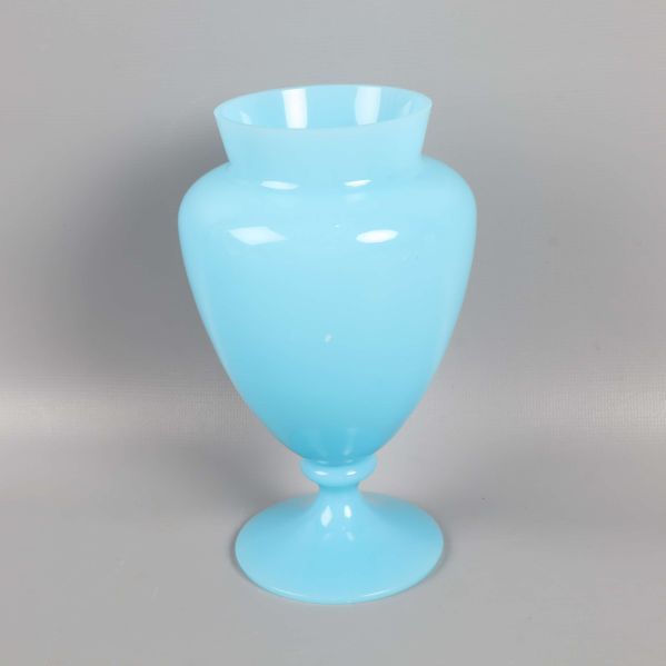 Blå vas med blank yta och hög fot mot grå bakgrund