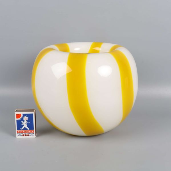 Vas med gula ränder jämte tändsticksask för storleksreferens
