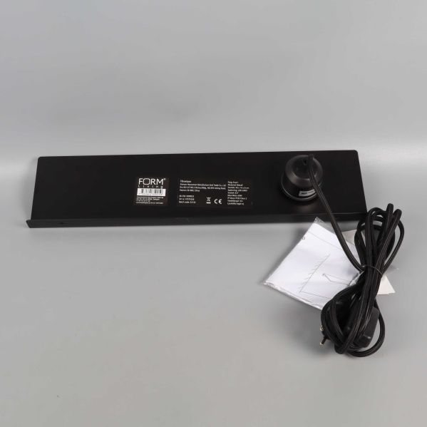 Vägglampa sedd underifrån med etikett och sladd