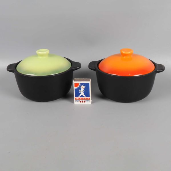 Grytor med grönt och orange lock bredvid tändsticksask