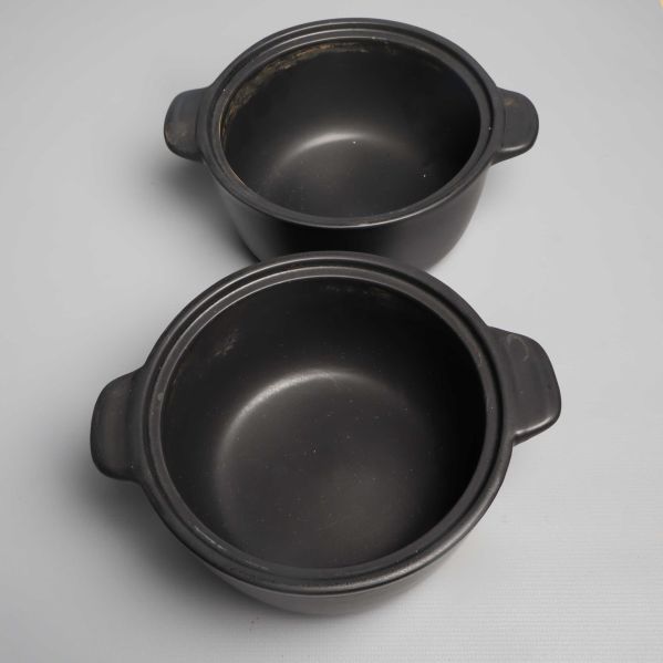 Två svarta grytor utan lock med slitna kanter synliga