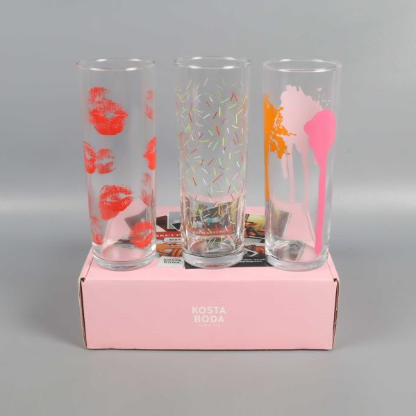 Höga glas med tryck av läppar, konfetti och färgstänk ovanpå rosa kartong