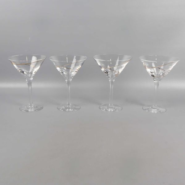 Fyra cocktailglas på rad på grå yta