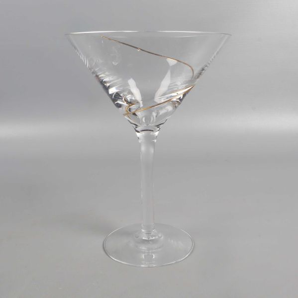 Ett cocktailglas med tydlig spiralformad gulddetalj