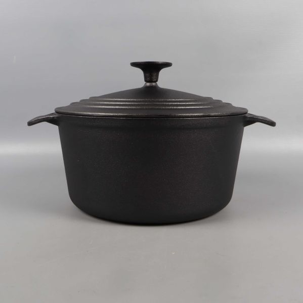 Framsidan av svart gjutjärnsgryta med lock