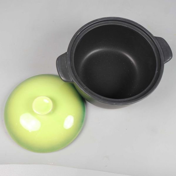 Öppen gryta med synligt svart inre och lock bredvid