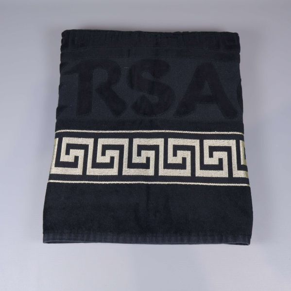 Svart handduk vikt med guldig mönsterbård synlig