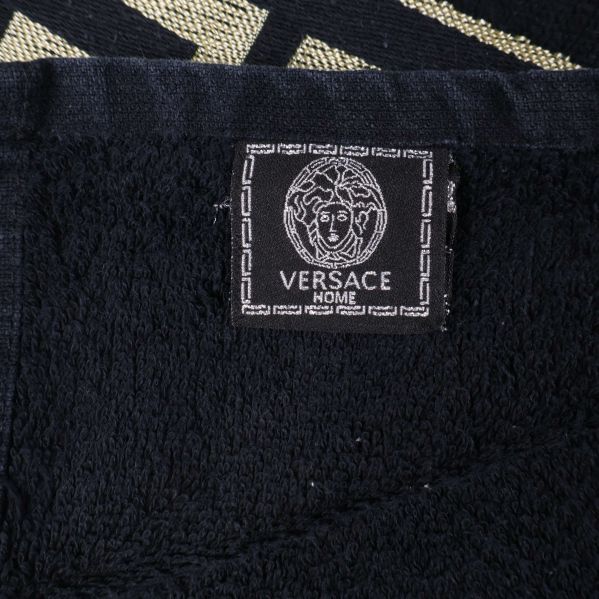 Närbild på svart etikett med Versace-logga på handduken