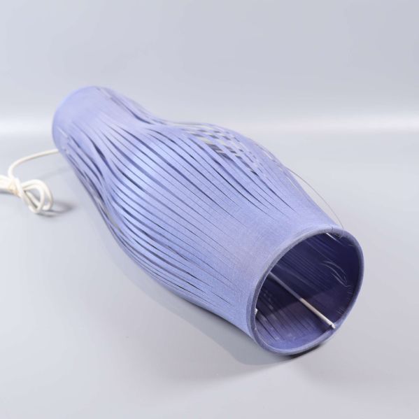 Taklampa i blå nyans liggande med synliga band