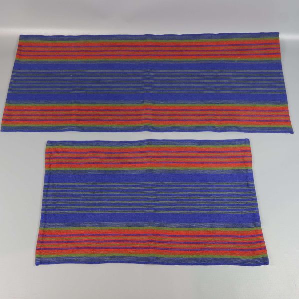 Två löpare i smårandigt tyg liggande platt