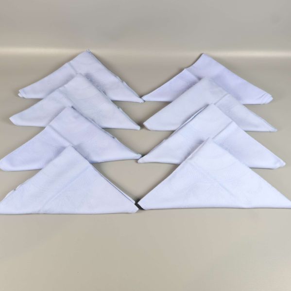 Åtta vikta blå linneservetter placerade i ett mönster