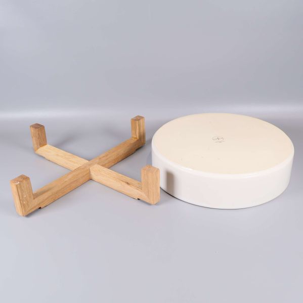 Träställning och vit skål visade separerade på grå bakgrund