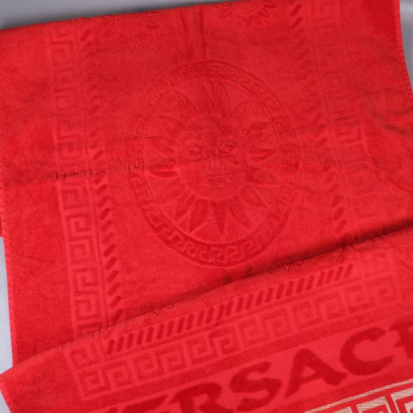 Närbild av röd handduk med solmotiv och bård