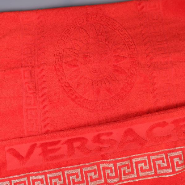 Närbild av solmotiv och VERSACE-mönster på handduken