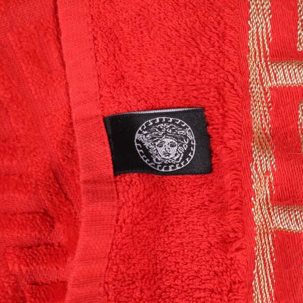 Svart etikett med Medusasymbol på röd handduk