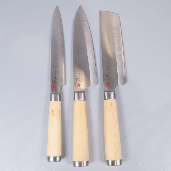 Tre köksknivar med ljusa trähandtag och olika blad