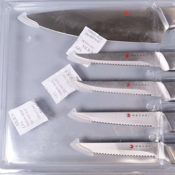 Närbild av blad med Hasaki-logga och etiketter på knivarna